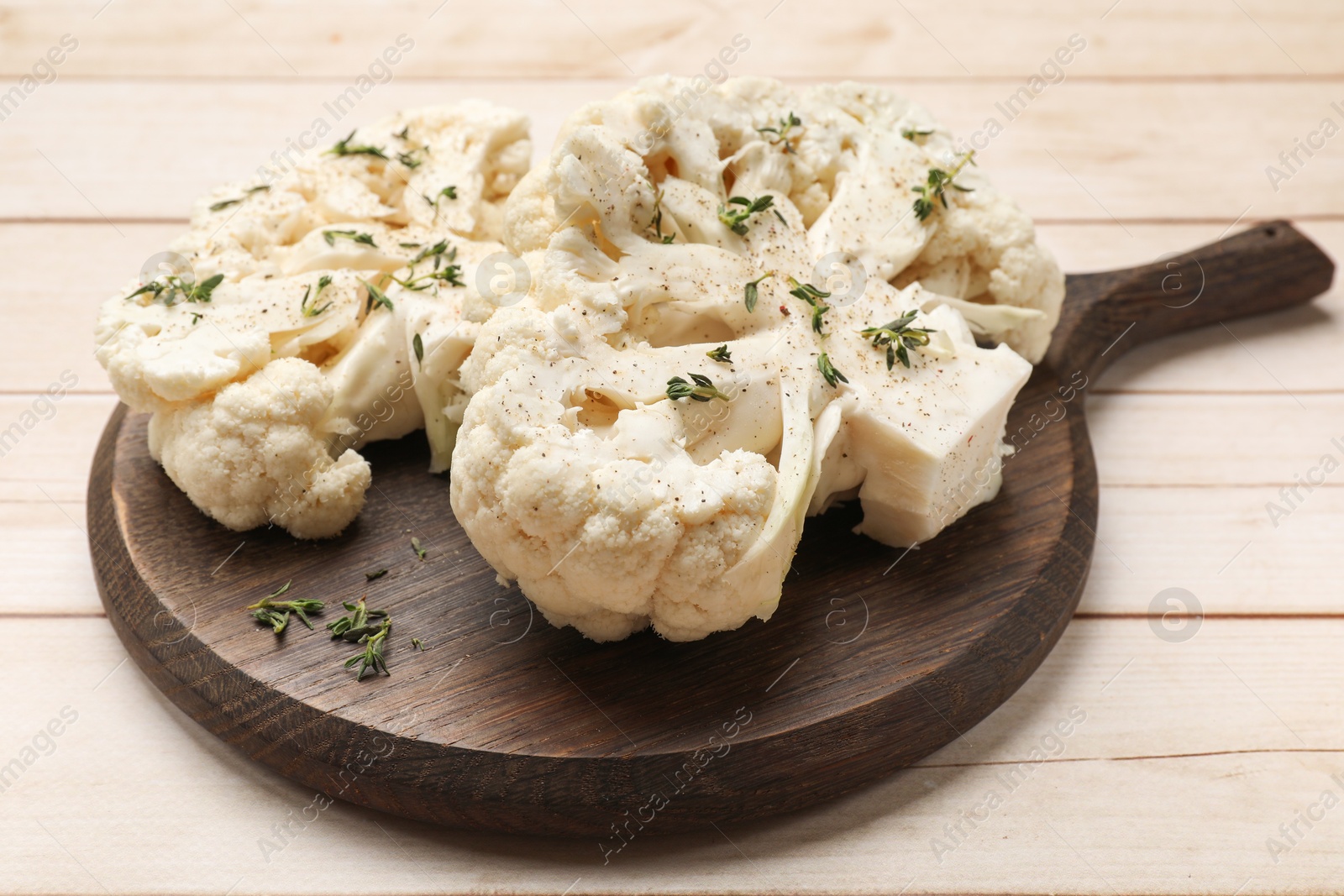 Photo of Uncooked cauliflower steaks with spices on wooden table, closeup