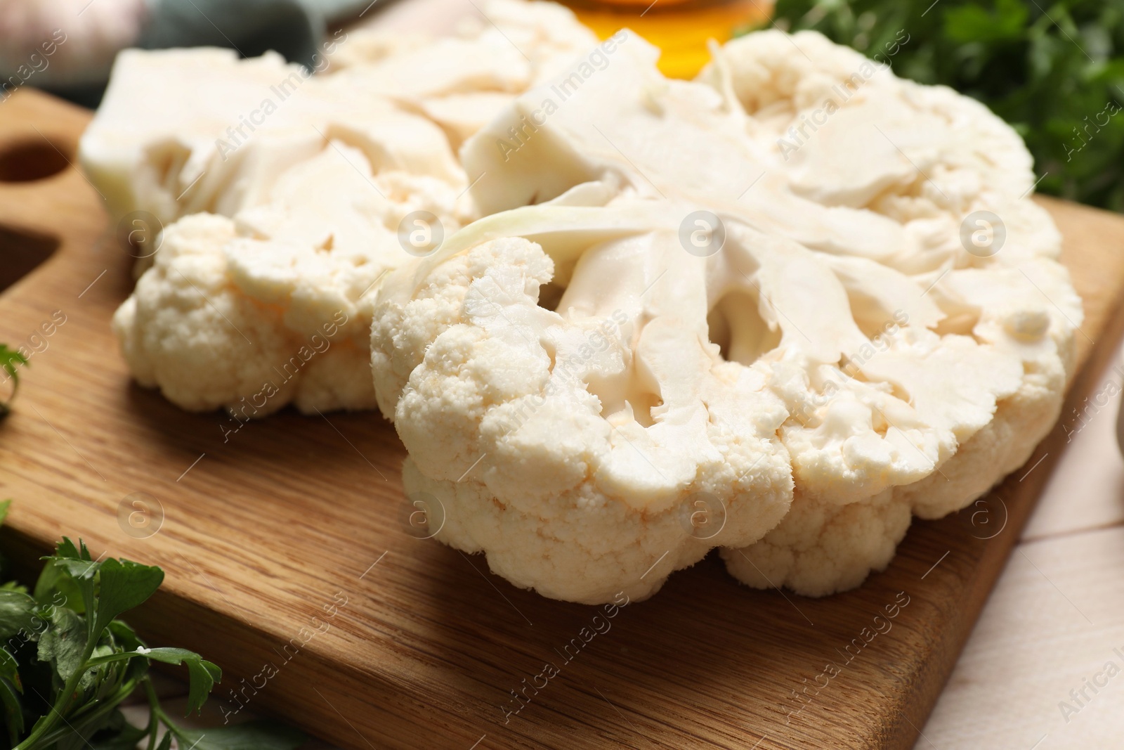 Photo of Uncooked cauliflower steaks and parsley on table, closeup