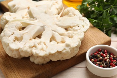 Photo of Uncooked cauliflower steaks and spices on wooden table, closeup