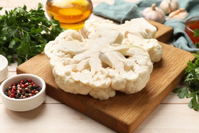 Photo of Uncooked cauliflower steaks, oil and spices on wooden table, closeup