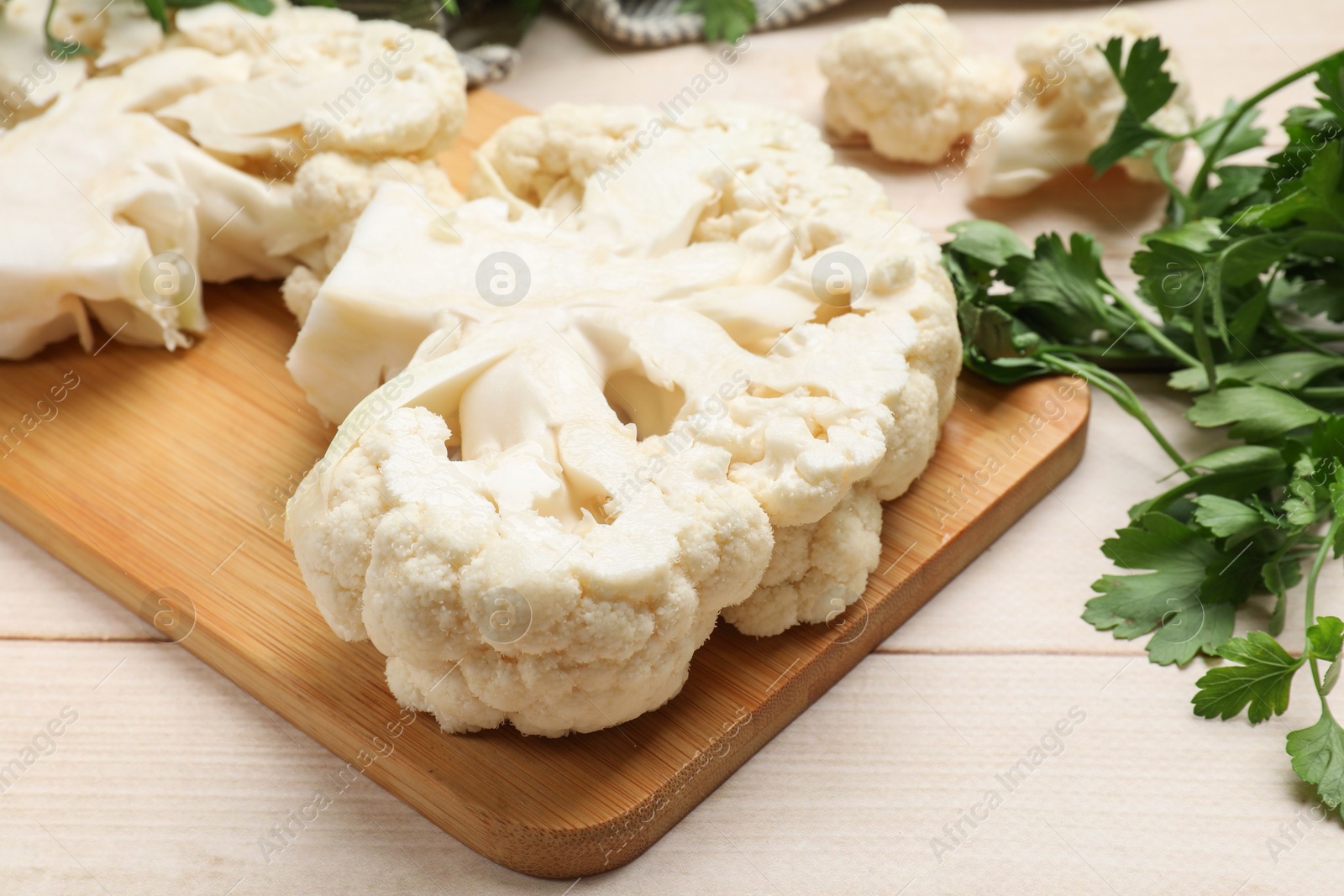 Photo of Uncooked cauliflower steaks and parsley on wooden table, closeup