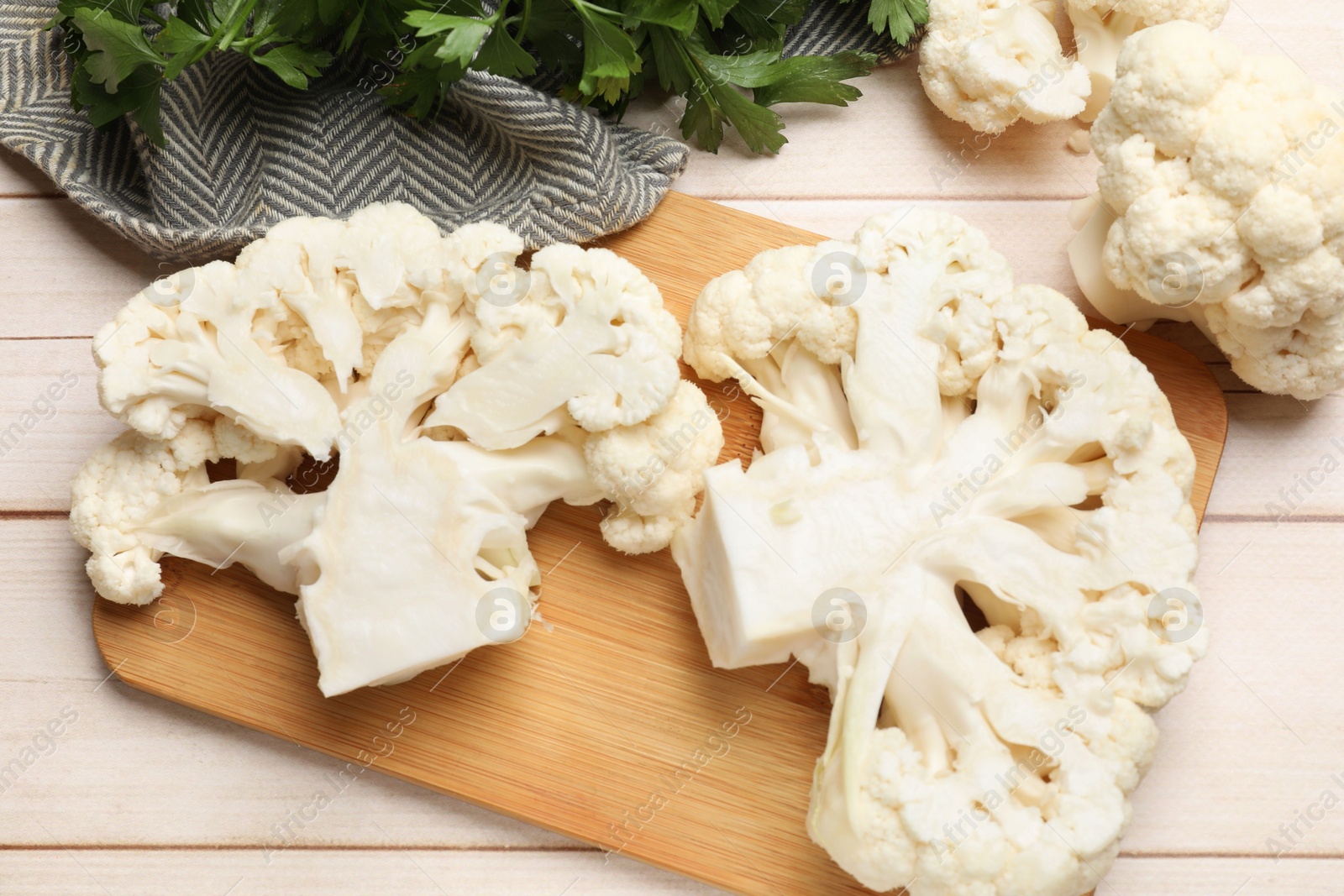 Photo of Uncooked cauliflower steaks and parsley on wooden table, flat lay