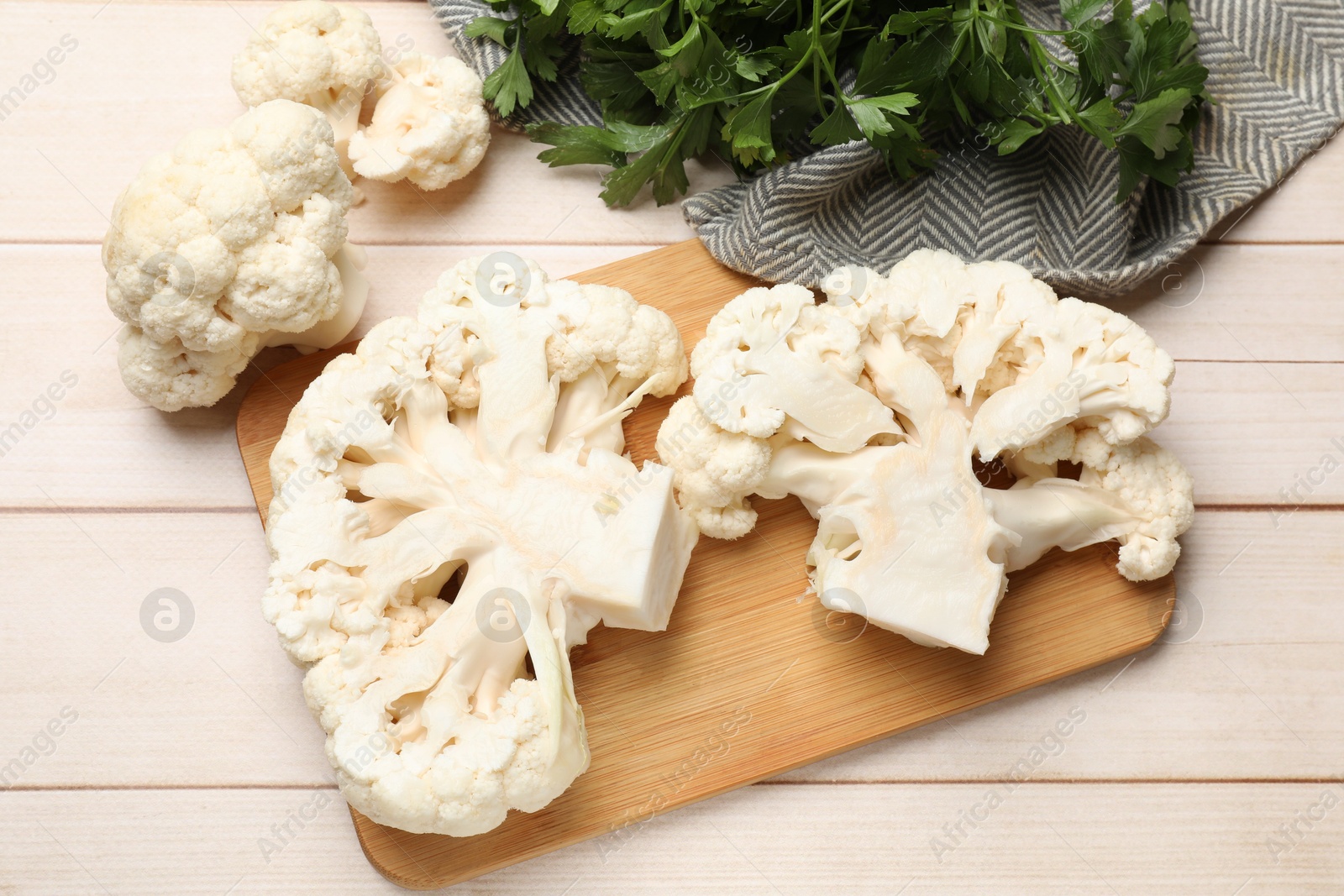 Photo of Uncooked cauliflower steaks and parsley on wooden table, flat lay