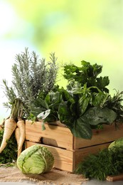 Different fresh herbs and cabbage on wooden table, closeup