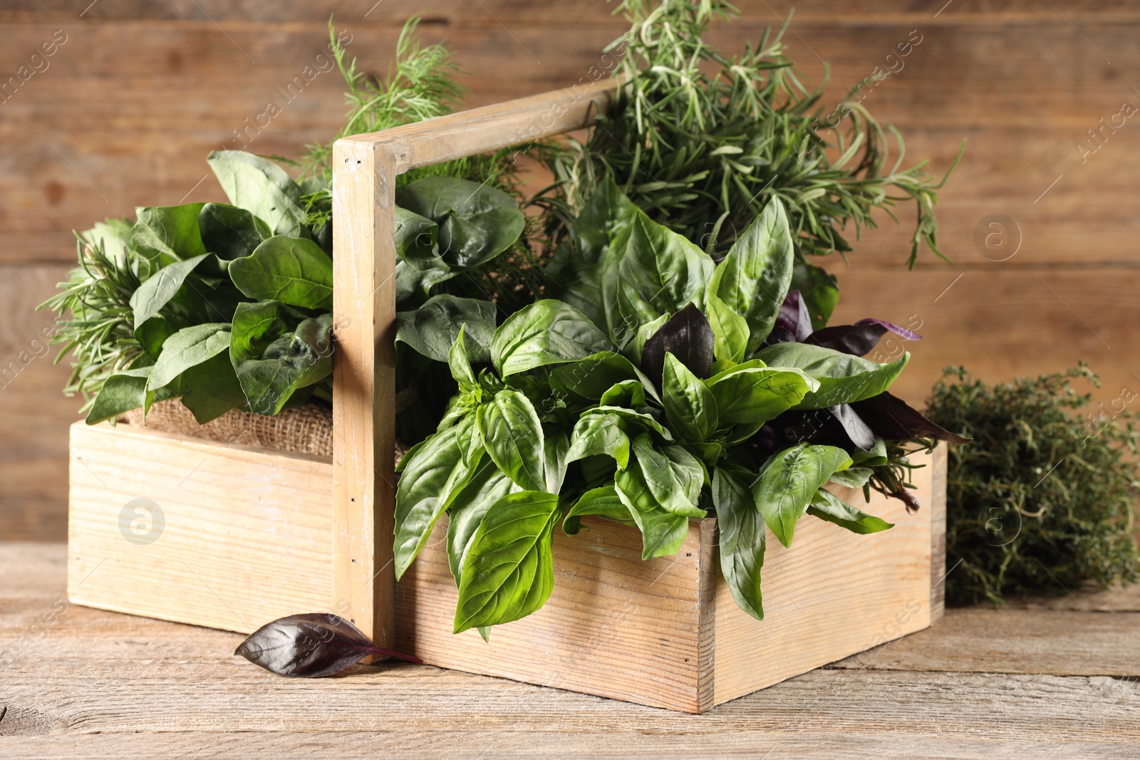 Photo of Different fresh herbs in basket on wooden table, closeup