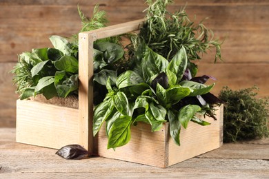 Photo of Different fresh herbs in basket on wooden table, closeup