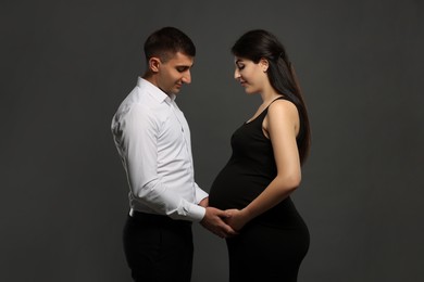 Photo of Beautiful pregnant woman with her husband on grey background