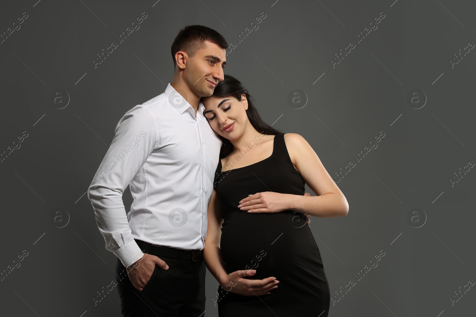 Photo of Beautiful pregnant woman with her husband on grey background