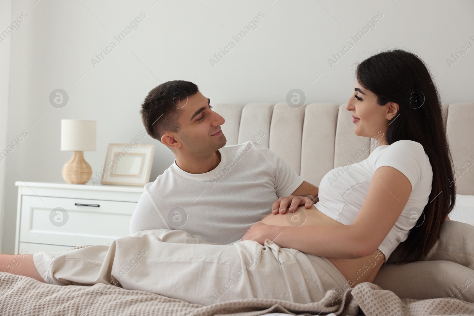 Photo of Beautiful pregnant woman spending time with her husband in bedroom