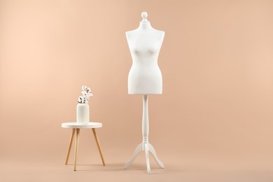 Female mannequin and vase on beige background