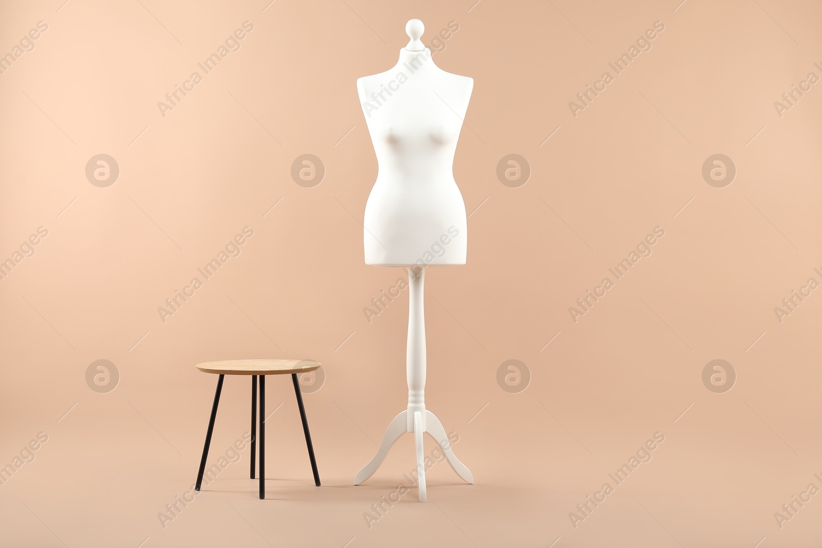 Photo of Female mannequin and stool on beige background