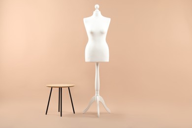 Photo of Female mannequin and stool on beige background