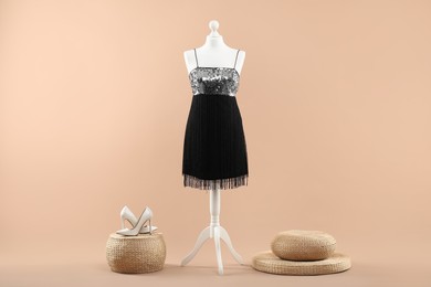 Mannequin with stylish dress and shoes on beige background