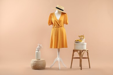 Mannequin with stylish dress, shoes and hat on beige background