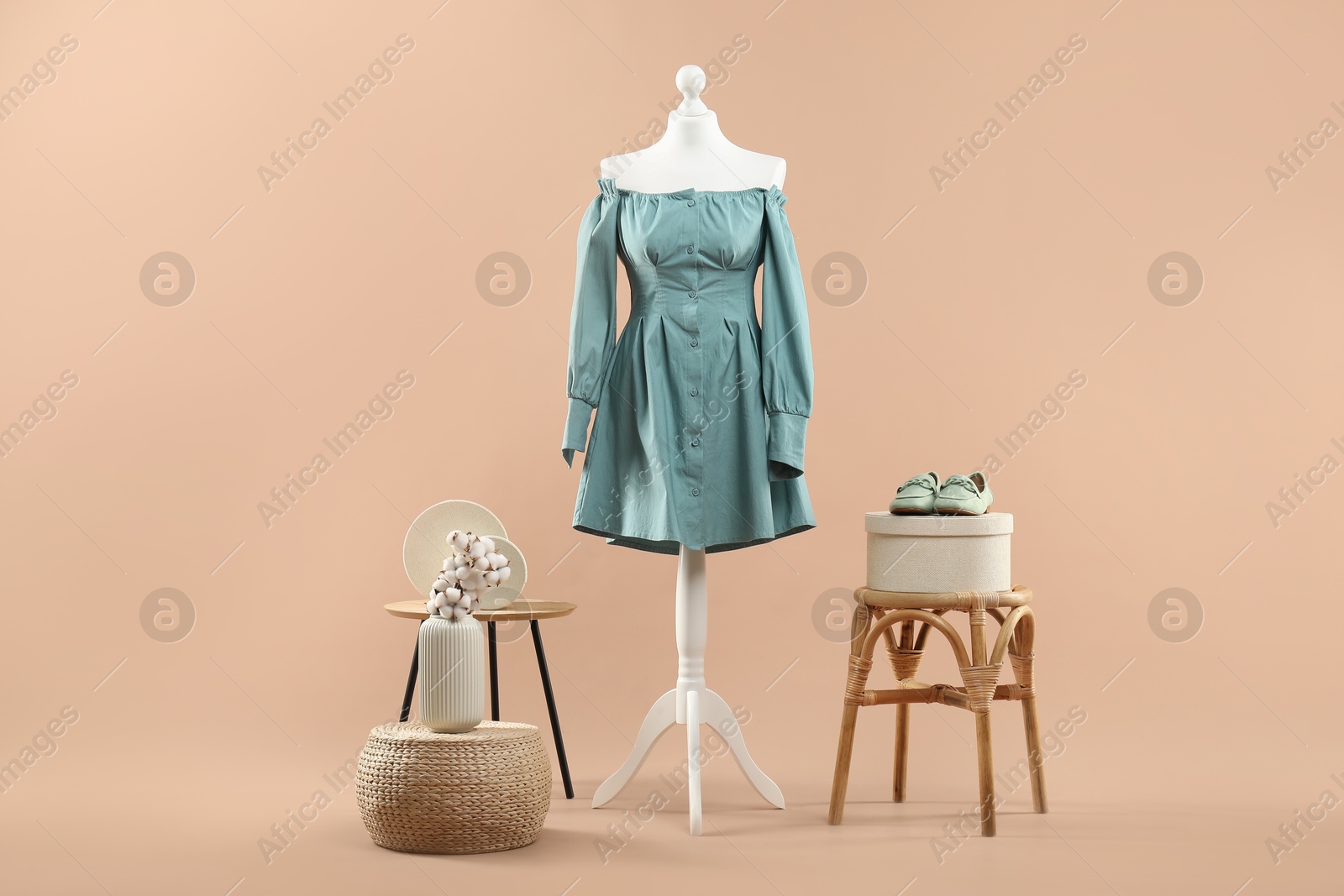 Photo of Mannequin with stylish dress, shoes and stools on beige background