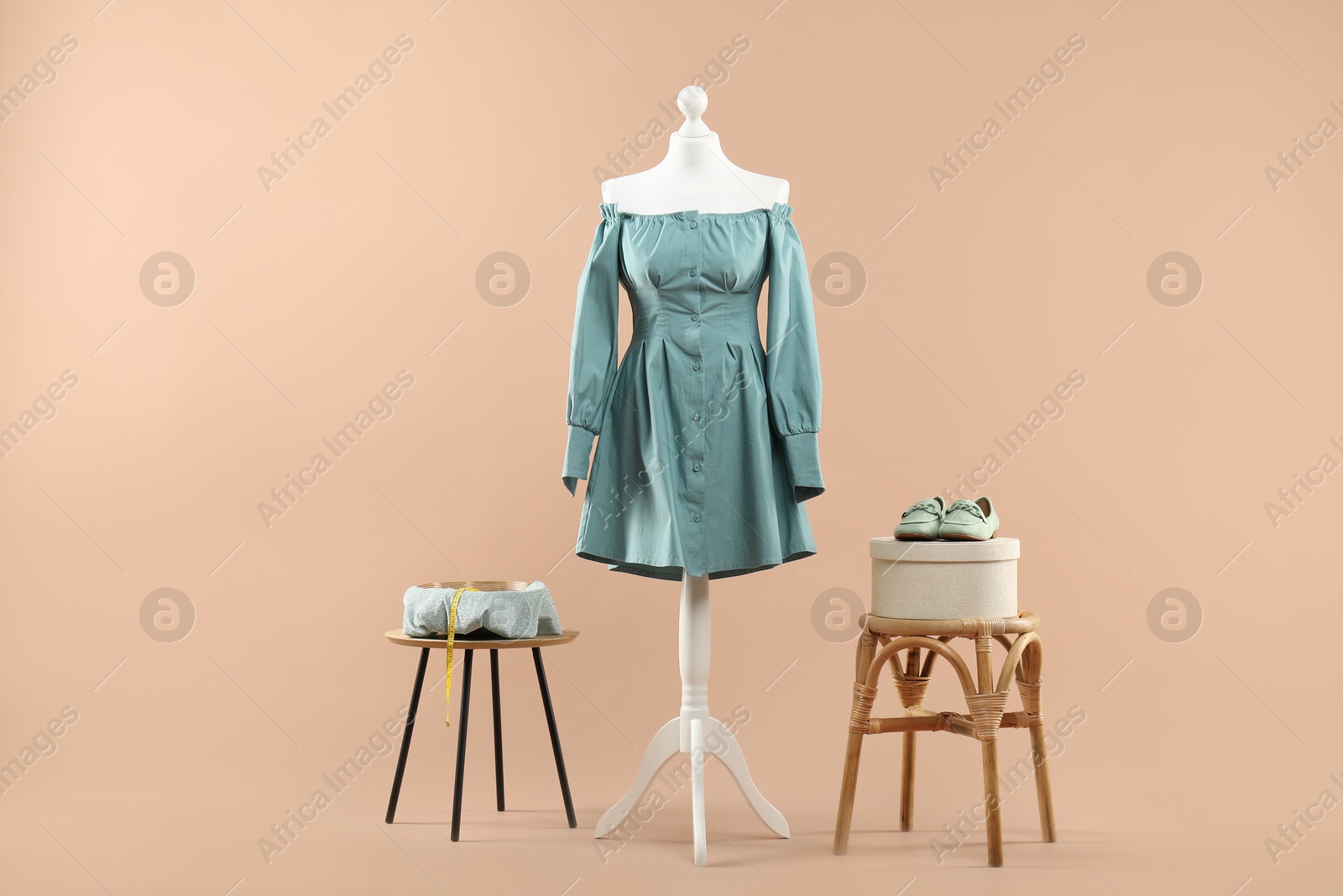 Photo of Mannequin with stylish dress, shoes and stools on beige background