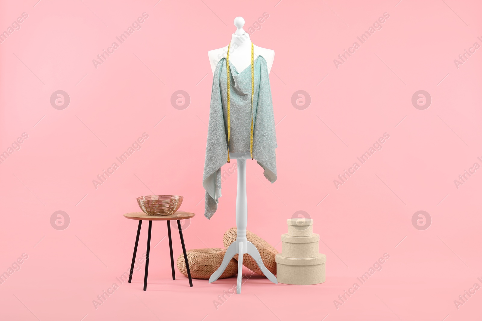 Photo of Mannequin, cloth, measuring tape and stool on pink background