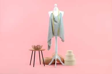 Photo of Mannequin, cloth, measuring tape and stool on pink background