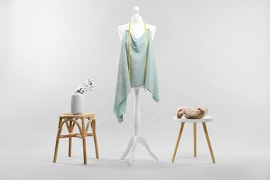 Mannequin, cloth, measuring tape and stools on light grey background