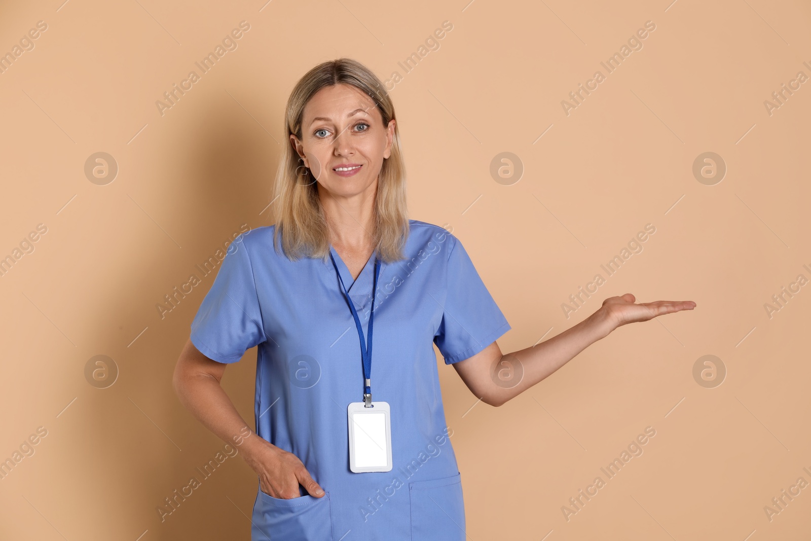 Photo of Portrait of nurse in medical uniform with badge on beige background