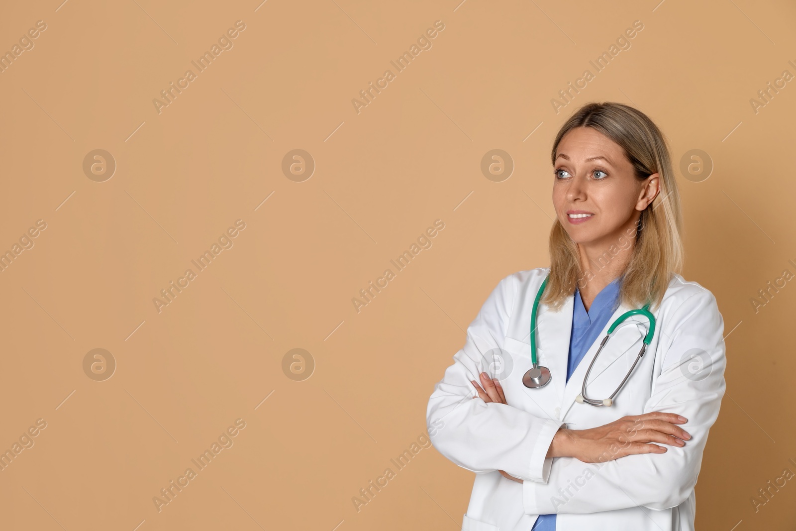 Photo of Portrait of doctor in medical uniform with stethoscope on beige background, space for text