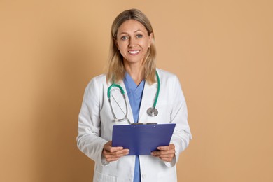 Photo of Portrait of doctor in medical uniform with stethoscope and clipboard on beige background