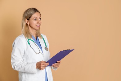 Doctor in medical uniform with stethoscope and clipboard on beige background, space for text