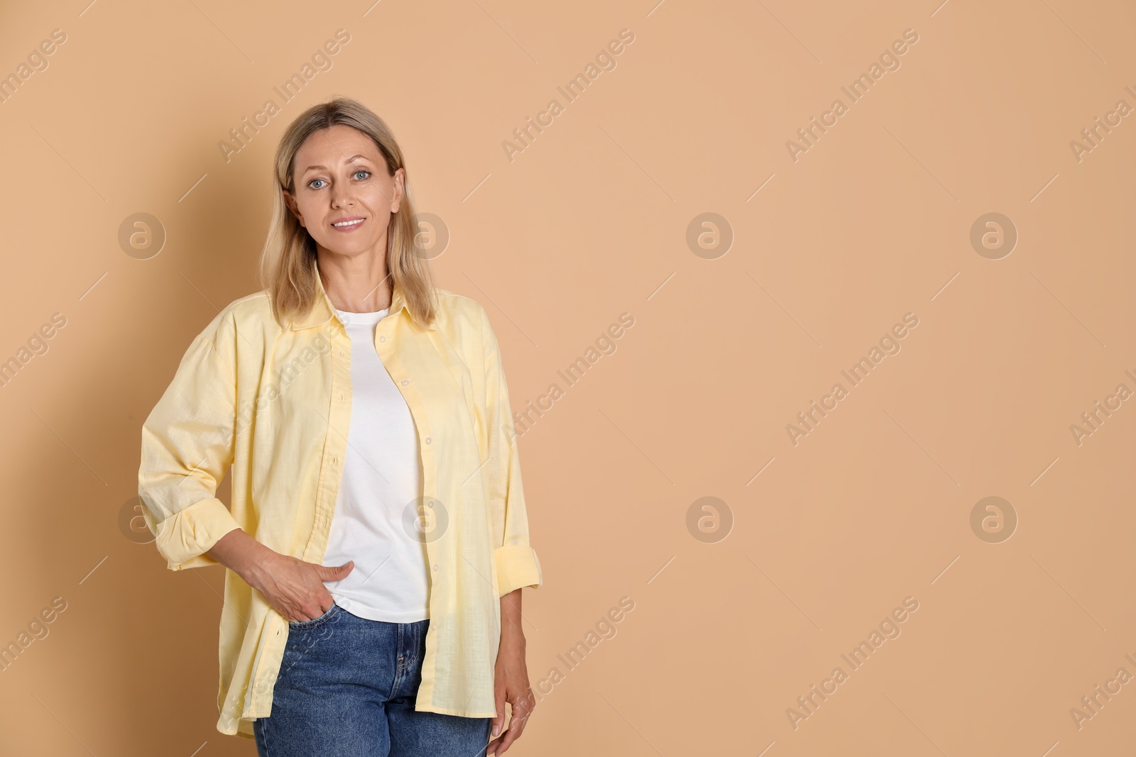 Photo of Portrait of beautiful smiling woman on beige background, space for text