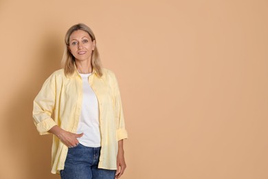 Photo of Portrait of beautiful smiling woman on beige background, space for text