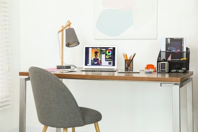 Photo of Fashion designer`s workplace with laptop and different supplies on table