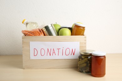 Photo of Different donation food products in crate on wooden table