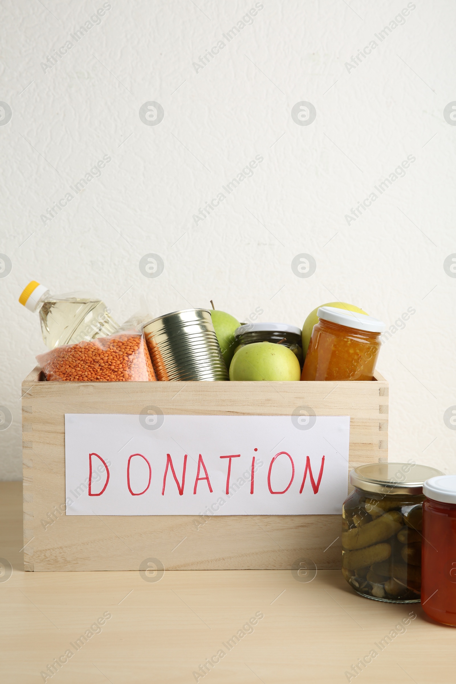 Photo of Different donation food products in crate on wooden table