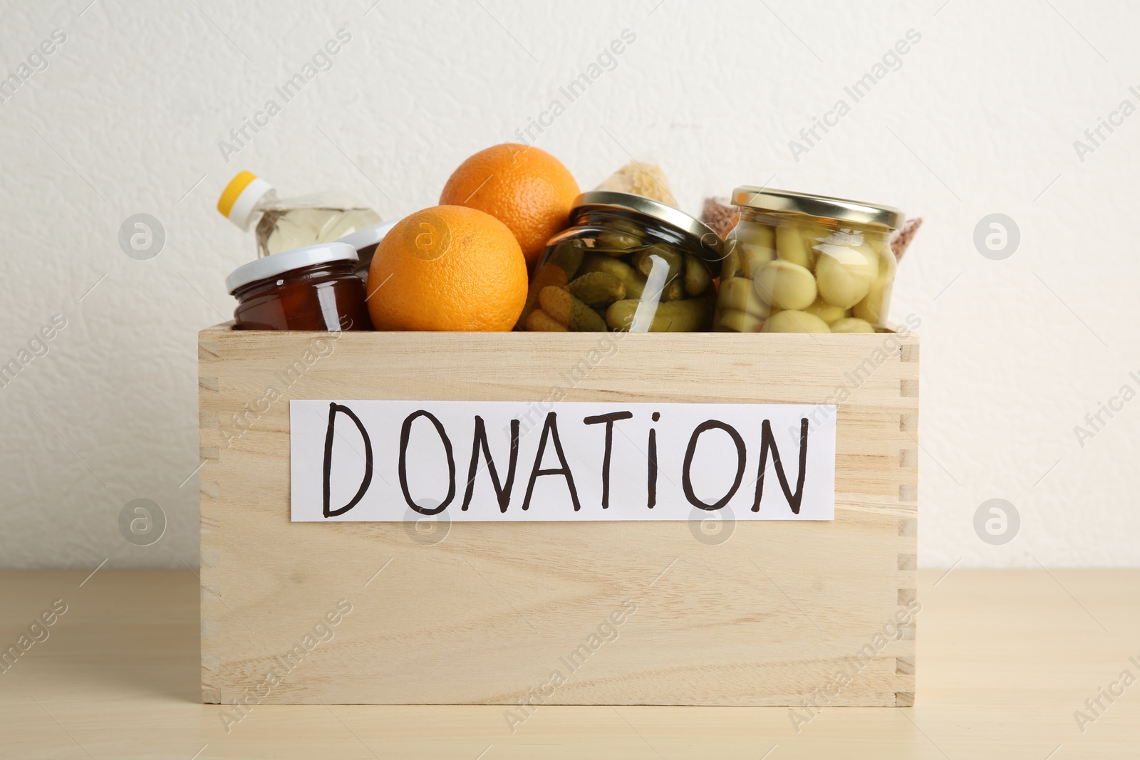 Photo of Different donation food products in crate on wooden table