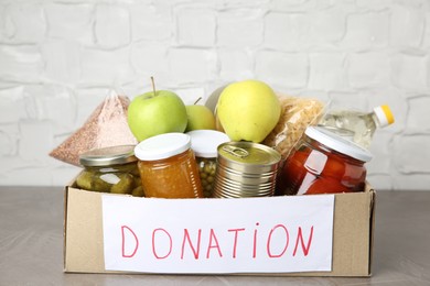 Photo of Donation food products in cardboard box on grey table