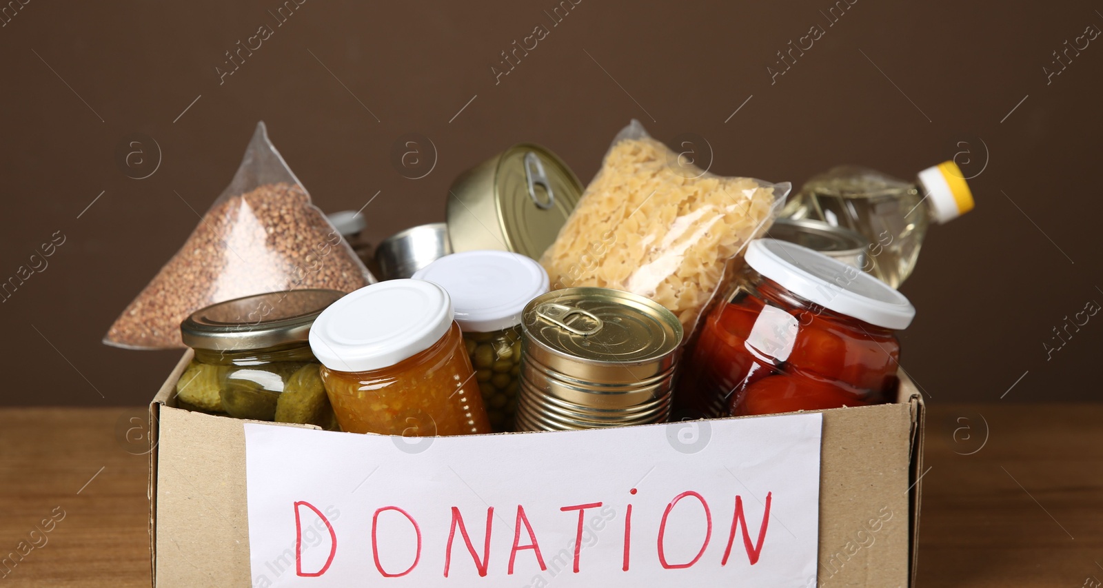 Photo of Donation food products in cardboard box on table, closeup