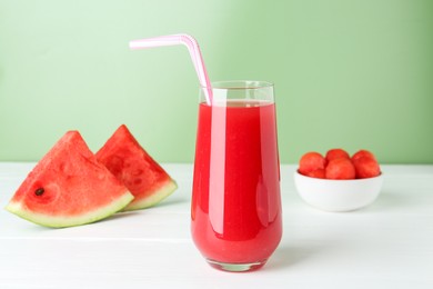 Photo of Tasty watermelon drink in glass and fresh fruit on white wooden table