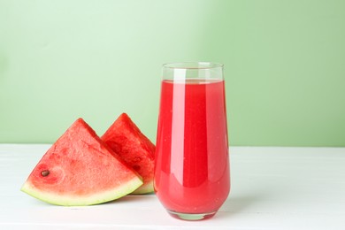 Photo of Tasty watermelon drink in glass and fresh fruit on white wooden table