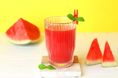 Photo of Tasty watermelon drink in glass and fresh fruit on white table, closeup