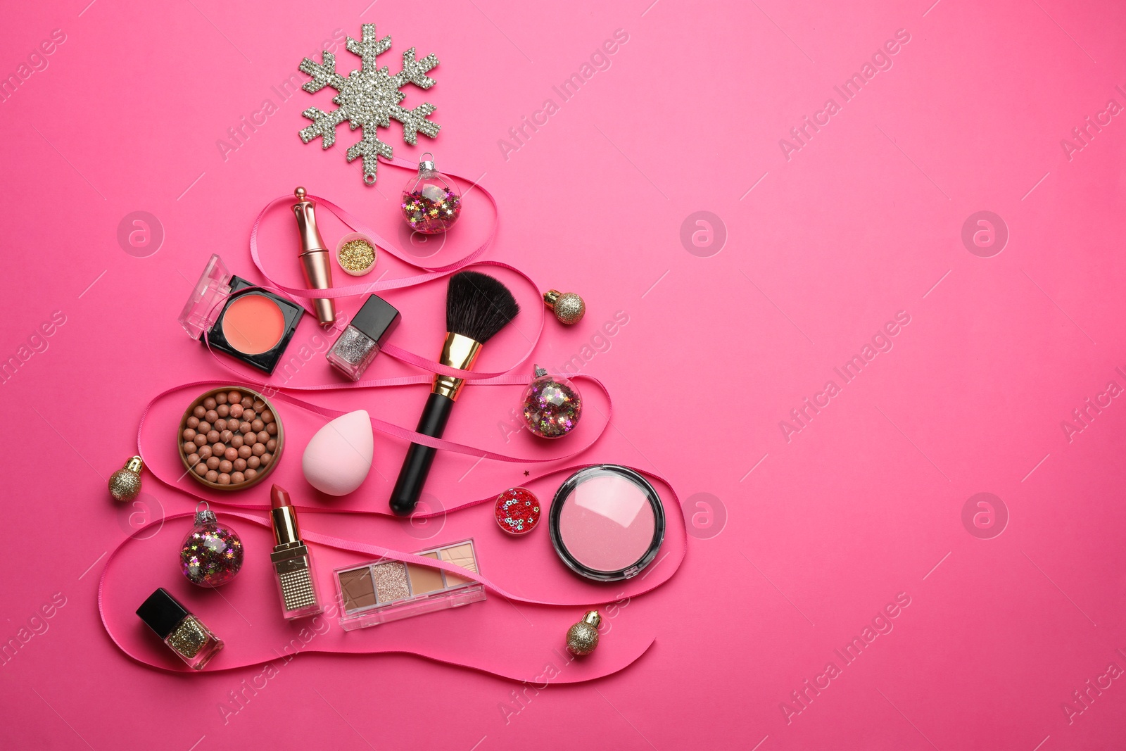 Photo of Christmas tree made of decorative cosmetic products and festive decor on pink background, flat lay. Space for text