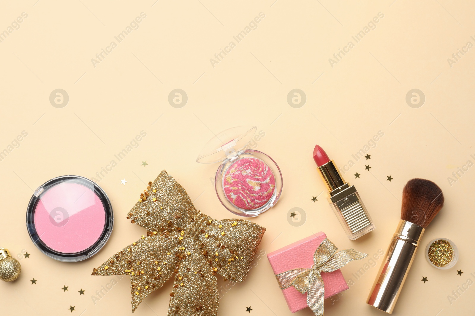 Photo of Flat lay composition with makeup products and Christmas decor on beige background. Space for text