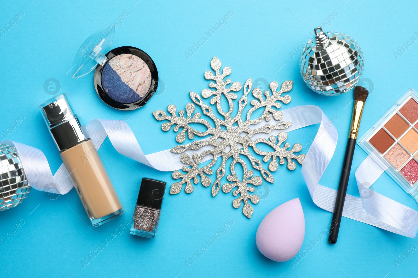 Photo of Flat lay composition with makeup products and Christmas decor on light blue background