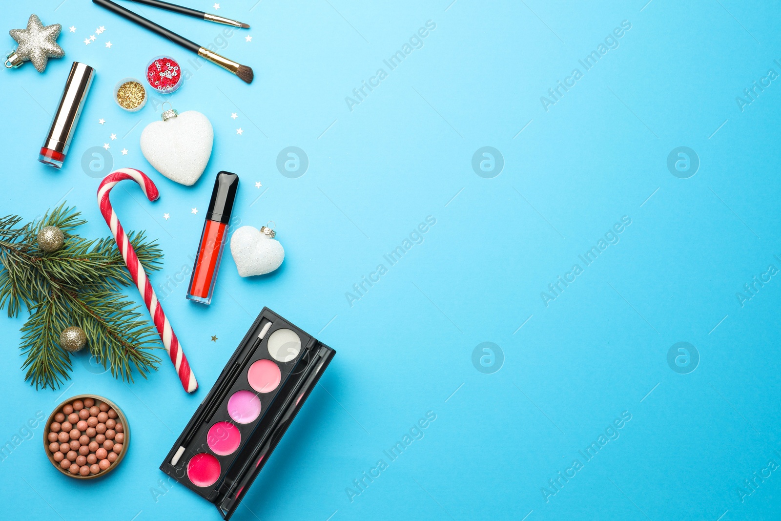 Photo of Flat lay composition with makeup products and Christmas decor on light blue background. Space for text