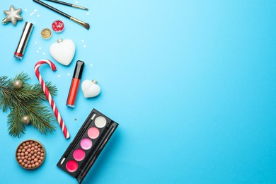 Photo of Flat lay composition with makeup products and Christmas decor on light blue background. Space for text