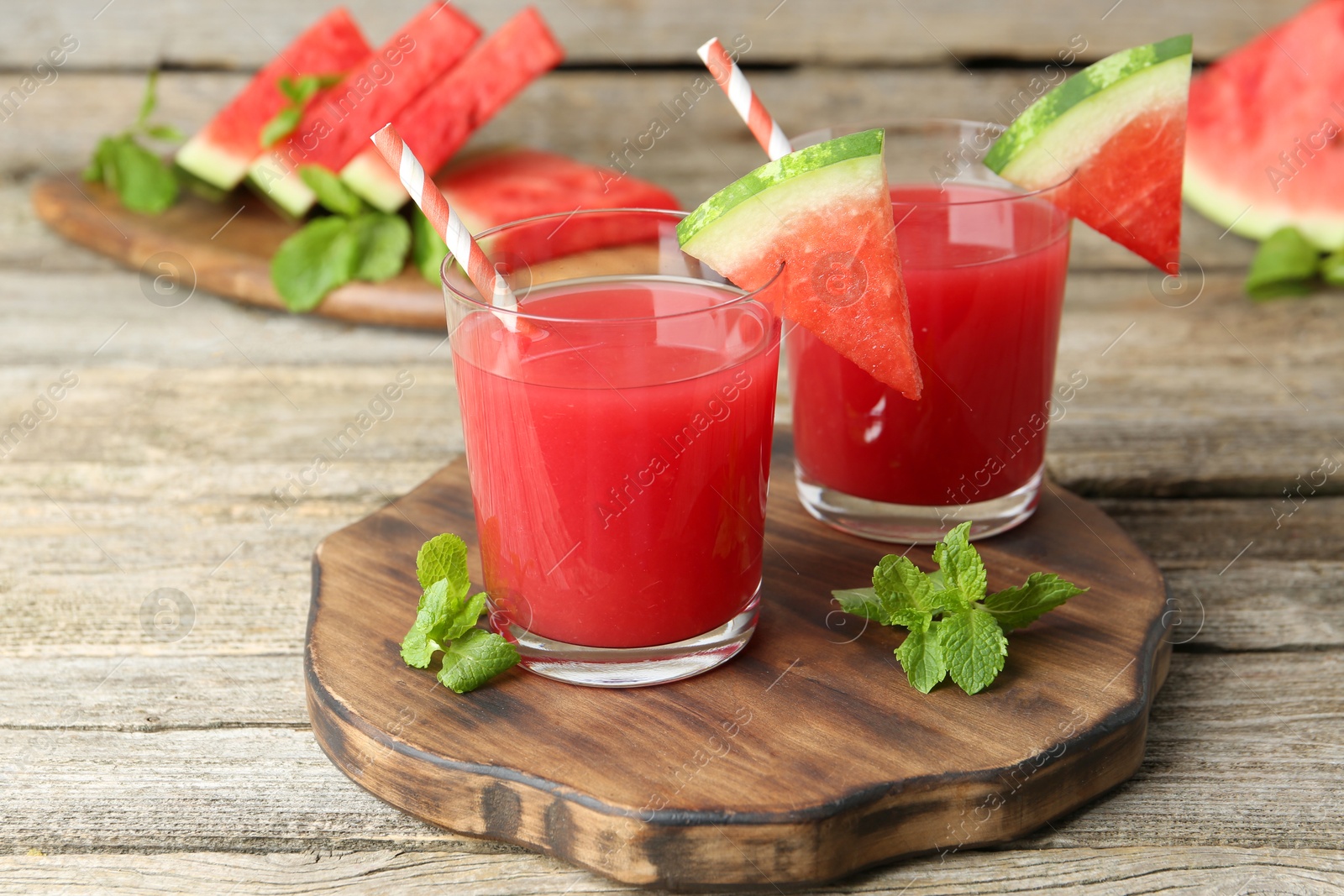 Photo of Tasty watermelon drink in glasses, fresh fruit and mint on wooden table