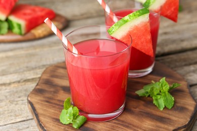 Photo of Tasty watermelon drink in glasses, fresh fruit and mint on wooden table, closeup