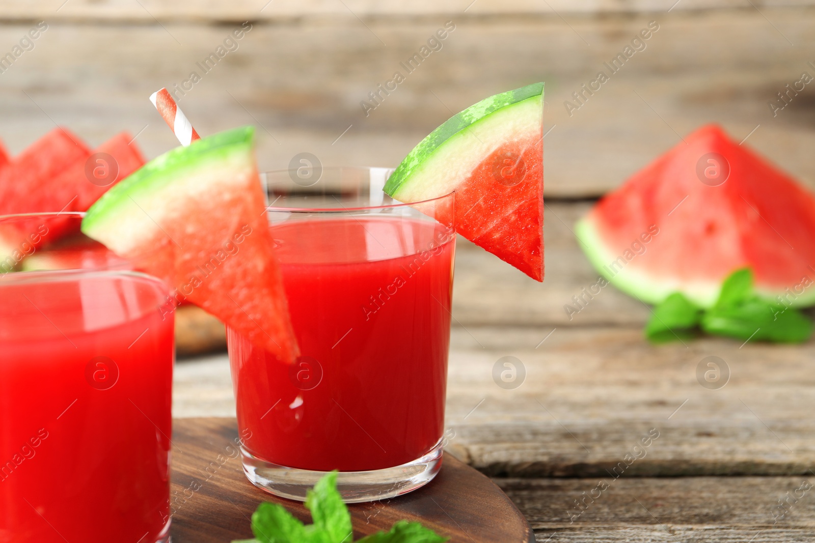 Photo of Tasty watermelon drink in glasses, fresh fruit and mint on wooden table, closeup