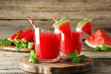 Photo of Tasty watermelon drink in glasses, fresh fruit and mint on wooden table, closeup