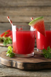 Photo of Tasty watermelon drink in glasses, fresh fruit and mint on wooden table, closeup