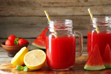 Photo of Tasty watermelon drink in mason jars and fresh fruits on wooden table, closeup