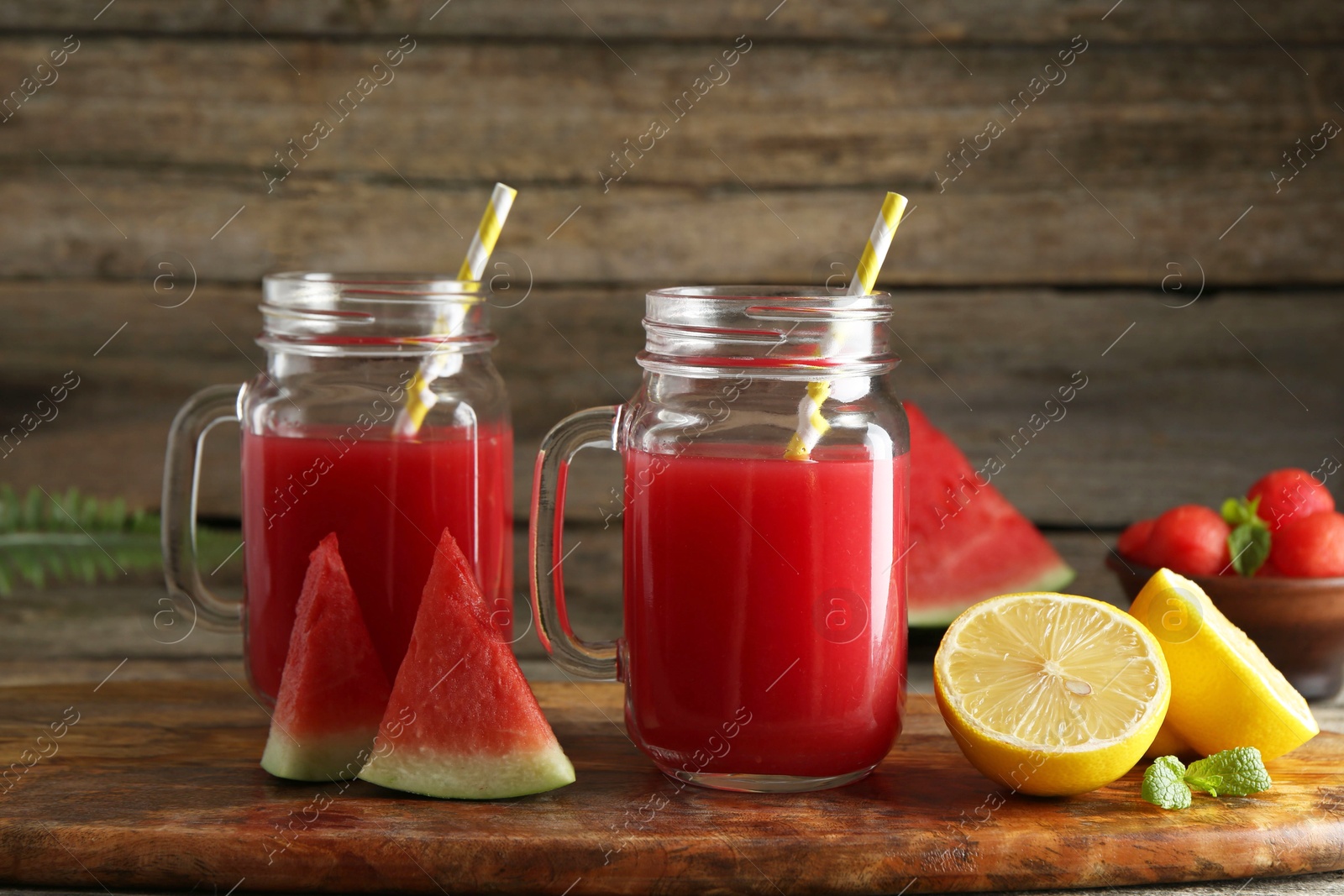 Photo of Tasty watermelon drink in mason jars and fresh fruits on wooden table